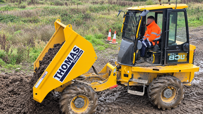 Operator in orange high-visibility clothing tipping soil from a yellow forward tipping dumper.